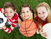 aerial shot of a group of kids standing on grass holding balls