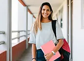 a woman holding a pink notebook smiling at camera