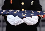 A soldier with gloves holding the American flag