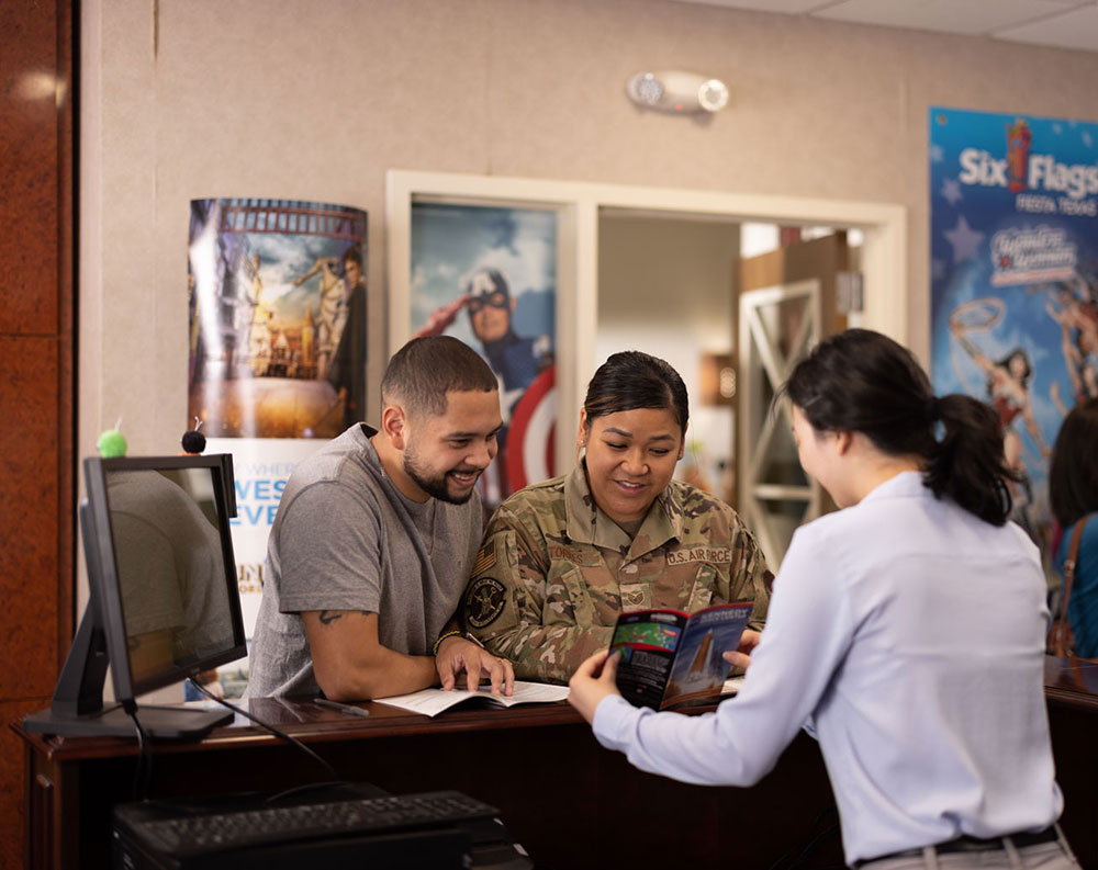 helpful woman in uniform assisting a man and a woman at a desk