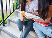 two women reading a book on the stairs