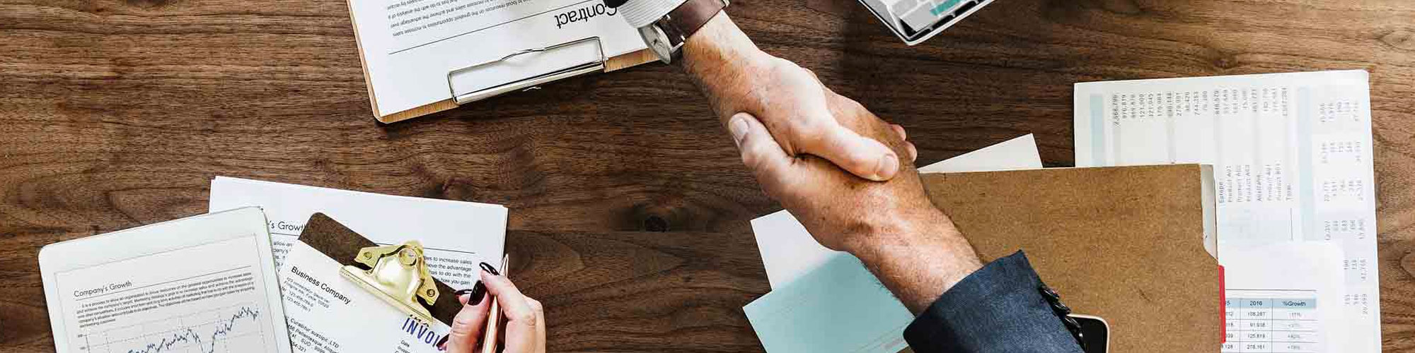 Business people shaking hands over papers and documents, sealing a deal