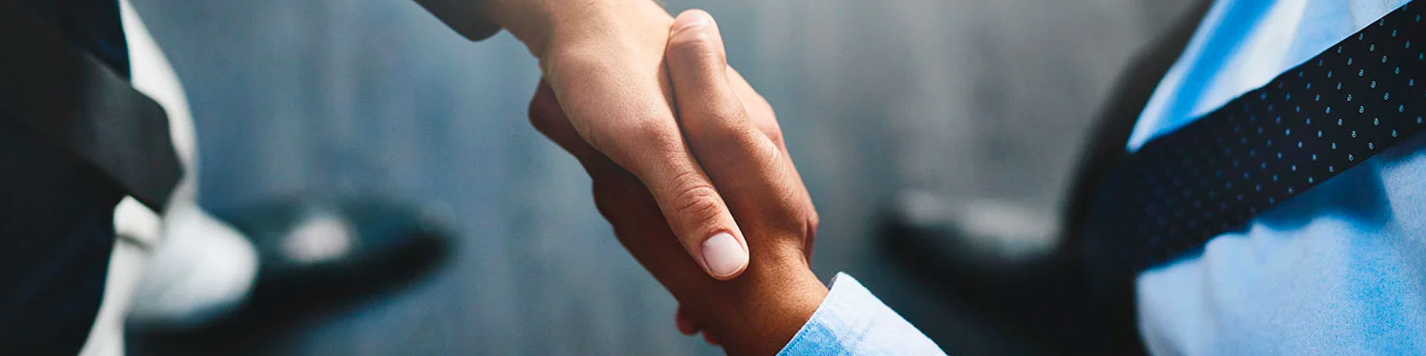 two professionals shaking hands in a formal business setting, symbolizing a successful agreement