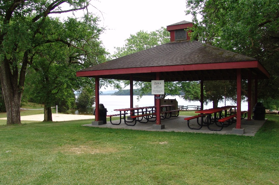 a picnic area with picnic tables and a lake