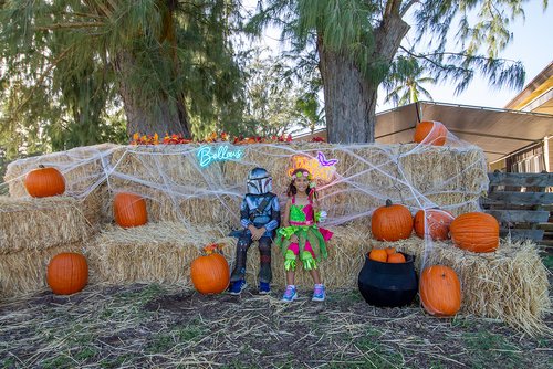 two children in clothing sitting on hay bales<br />
