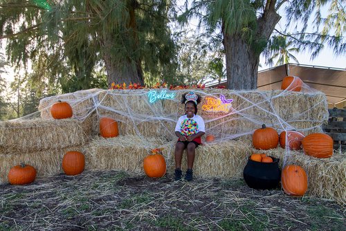 a kid in clothing sitting on hay bales<br />
