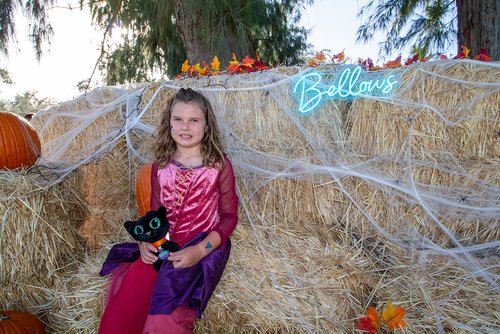 a kid in costumes two children in costumes sitting on hay bales<br />
