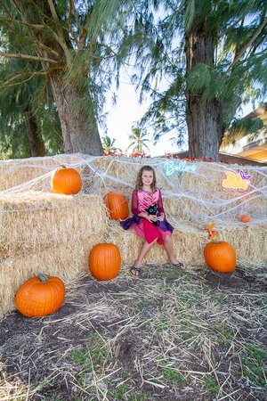 a kid in clothing sitting on hay bales<br />
