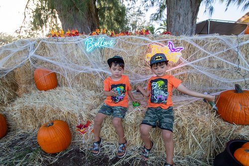 two kids sitting on hay with pumpkins<br />
