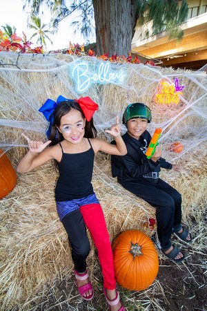 two kids sitting on hay with pumpkins<br />
