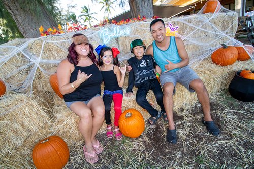 a group of people sitting on hay with pumpkins