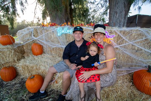 a group of people sitting on hay with pumpkins