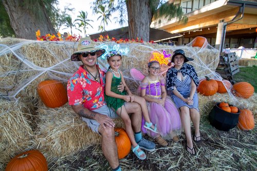 a group of people sitting on hay with pumpkins