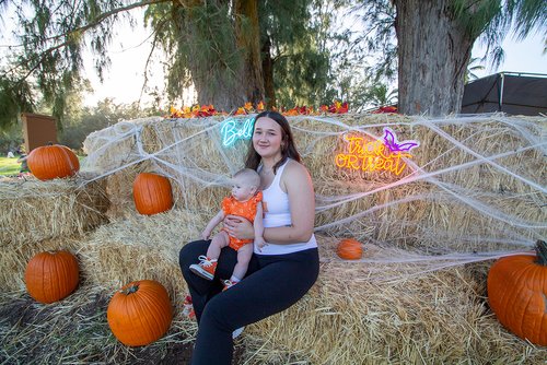 a person sitting on hay with a baby