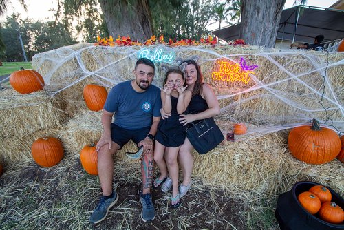 a group of people sitting on hay with pumpkins and lights