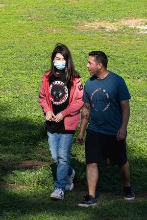 a person and person wearing face masks walking in a grassy field