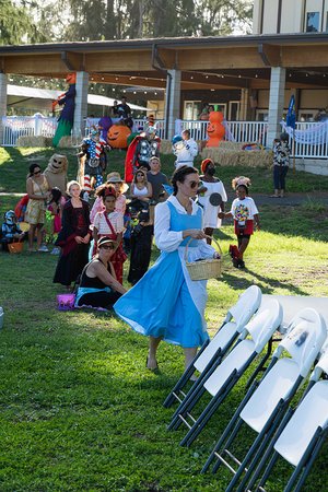 a person in a blue dress walking in a yard with people in clothing