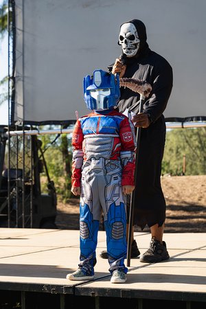 a person in a garment holding a stick next to a child in a garment