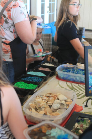 a group of people standing next to a table with different colored objects