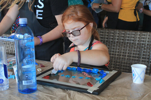 a child sitting at a table with a glass and a bottle of water