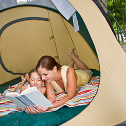 mom and daughter reading book in the tent