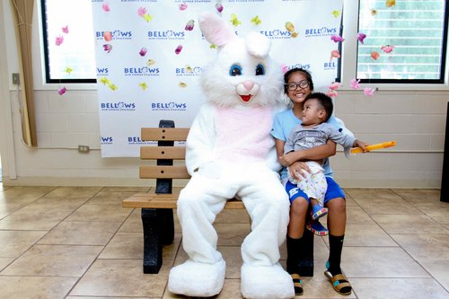 a child sitting on a bench with a person in a rabbit garment<br />
