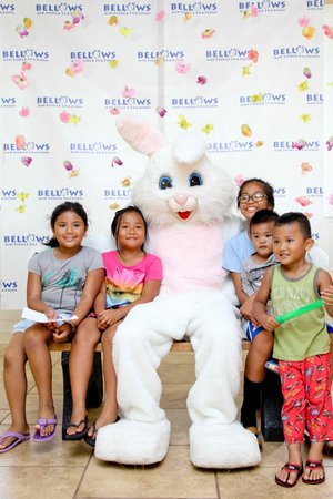 a group of kids sitting on a bench with a person in a bunny garment<br />
