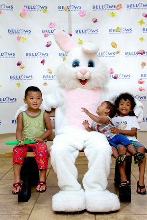 a group of kids sitting on a bench with a person in a bunny garment<br />
