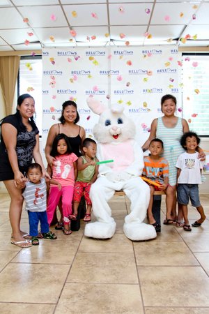 a group of kids sitting on a bench with a person in a bunny garment<br />
