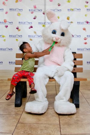 kid sitting on a bench with a person in a bunny garment<br />
