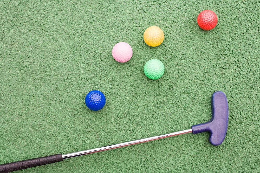 a golf club and balls on green surface