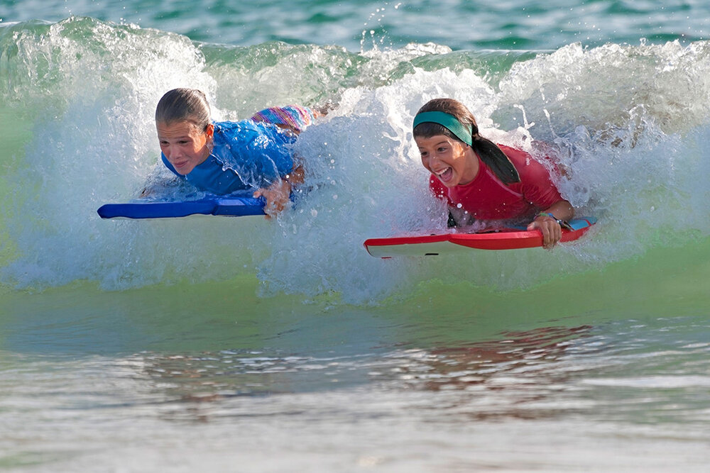 two childs on boogie boards in the ocean<br />
